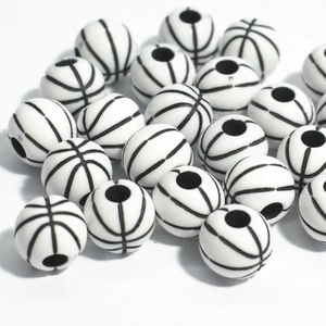 Macro shot of 50 black and white basketball-shaped acrylic beads with pre-drilled holes