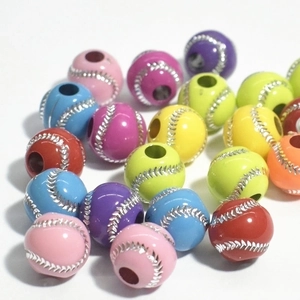 Macro detail of colorful baseball-shaped acrylic beads with silver stitching for DIY crafts