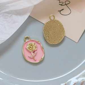 Detailed view of alloy rose charms with pink enamel, faux pearls, and golden metal back