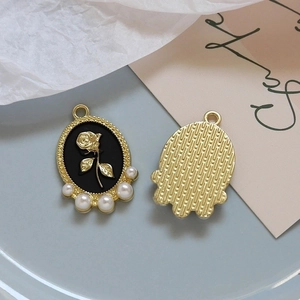 Detail of vintage rose pendant with black enamel, white pearls and gold metal finish