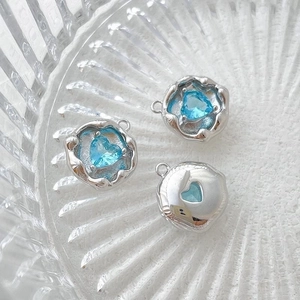 Macro shot of 14k gold-plated heart charms with blue cubic zirconia on glass surface