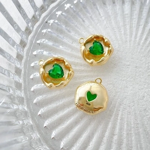 Detailed macro of 14k gold plated heart pendants with green zircon in a glass tray