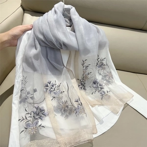 Detail of grey gradient scarf featuring delicate floral embroidery and gold glitter trim