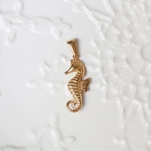 Detailed close-up of a 18K gold-plated seahorse pendant with polished finish details