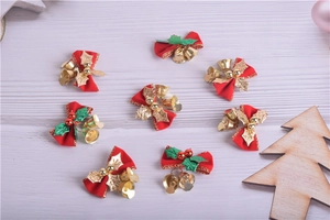 Detail of eight red fabric Christmas bows with gold bells and green leaves on wood