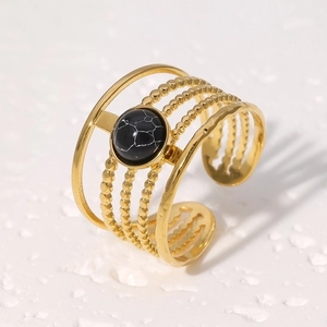 Macro detail of bohemian multilayer gold ring featuring black natural stone center