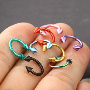 Colorful stainless steel C-shaped nose rings and ear studs displayed on fingers