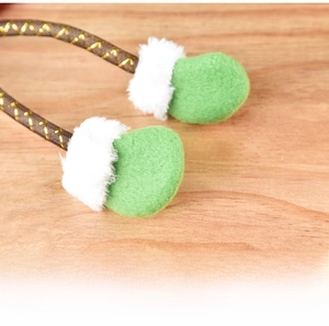 Macro detail of Christmas plush doll green feet with soft white fur trim and woven lanyard