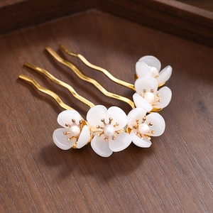 Detailed view of gold hair comb with five white frosted flowers and tiny pearls