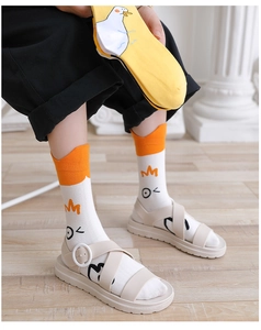 Detailsicht auf Socken mit Entenmuster und beige Sandalen auf hellem Holzboden