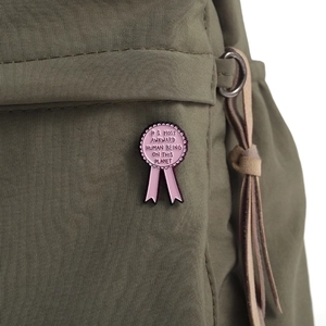 Macro detail of a pink enamel award ribbon brooch pinned on a green nylon backpack