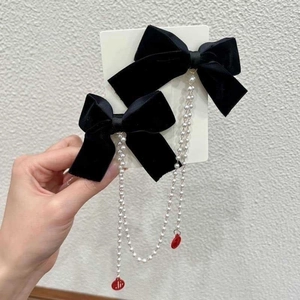 Close-up of velvet bow hair clips with long pearl chains and red Fu character pendants