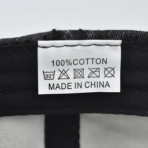 Detail shot of the 100% cotton washing label and internal stitching on black baseball cap
