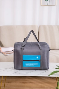 Detail of grey foldable travel bag with blue trolley sleeve and white airplane icon