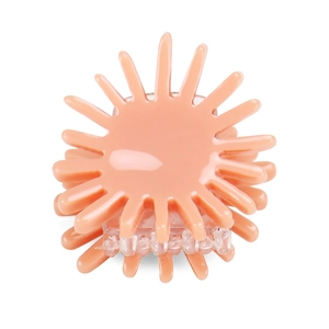 Detail of coral pink sun-shaped hair claw clip with glossy acetic acid finish