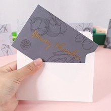 Many thanks card with gold lettering and white envelope in a warm lifestyle setting