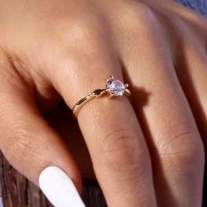 Close-up of a minimalist gold plated ring with a clear zircon stone on a model finger