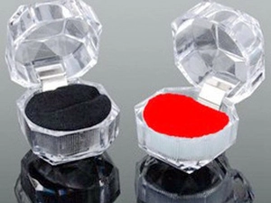 Nahaufnahme einer achteckigen Acryl-Ringbox mit rotem und schwarzem Samteinsatz