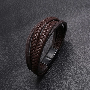 Detail of multi-layer brown braided leather bracelet with black magnetic clasp closure