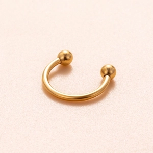 Golden titanium horseshoe ring with ball ends for nose or cartilage piercing on pink background