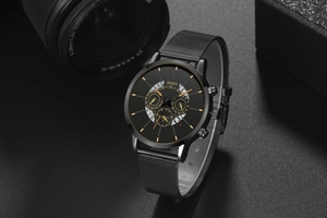 Detail view of black mesh band watch with gold hands and Geneva logo on a dark background