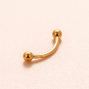 Close-up of golden titanium curved barbell with internally threaded screws for piercing