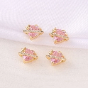 Macro detail of four pink heart planet pendants for DIY jewelry making on white fabric