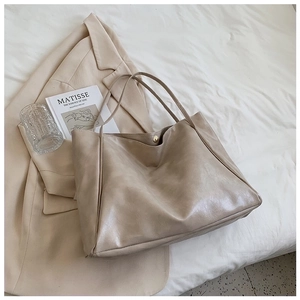 Close-up of beige faux leather tote bag showing textured finish and metal snap button