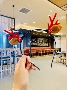 Detail of a Christmas reindeer antler headband with red plush ears and berry accents