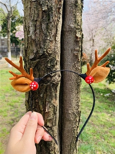 Detailed close-up of plush brown reindeer antlers headband with red mushroom accents