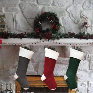 Detail of red grey and green knitted Christmas stockings with white trim on a fireplace