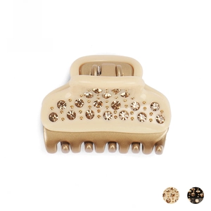 Close-up of cream acetate hair claw clip with champagne rhinestones and gold teeth