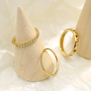 Detailed close-up of three gold rings with crystals on a wooden cone display stand