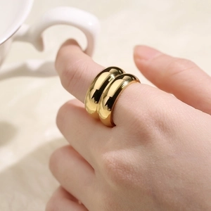 Close-up of dual chunky gold dome rings in polished titanium steel on model hand