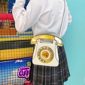 Close-up of a white vintage telephone bag featuring a rotary dial and receiver handle