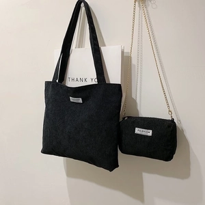 Detail of black corduroy tote bag set with small gold chain pouch and fashion label