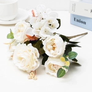 Elegant white artificial rose bouquet with green leaves on a clean white desk setup