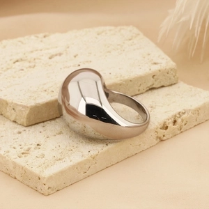 Macro shot of silver organic drop ring on textured stone showcasing mirror-like polish