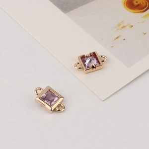 Detail showing two golden square connectors with pink zircons for DIY jewelry making