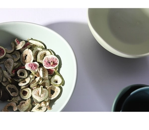 Overhead view of matte ceramic lotus bowls in soft tones filled with dried figs