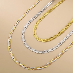 Dettaglio di collane a catena piatta intrecciate in oro, argento e finitura tricolore