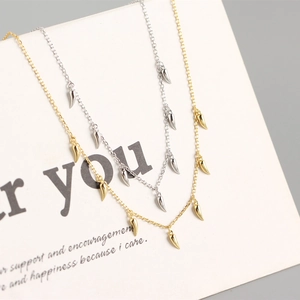 Macro detail of gold and silver S925 sterling silver chili pendant necklaces on card