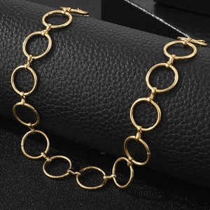 Gros plan d'un collier à maillons cercles dorés sur une texture en cuir noir élégante