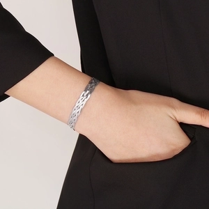 Close-up of a silver braided titanium steel bracelet worn on a wrist with a black jacket