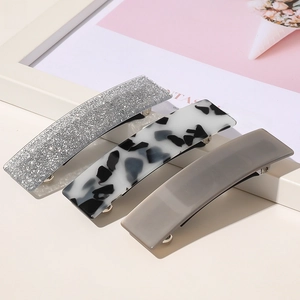 Détail de trois barrettes en acétate avec paillettes argentées, écaille et motifs gris