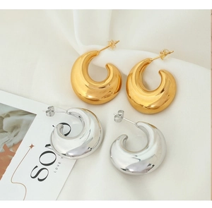 Detail shot of hollow C-shape hoop earrings in gold and silver on soft white fabric