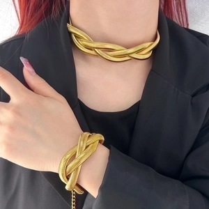 Detail of gold twisted weave necklace and bracelet set worn on a black blazer