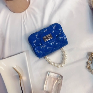 Close-up of blue quilted PVC mini bag with pearl handle and silver twist lock on white cloth