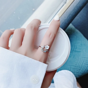 Close-up of a silver flower ring with white enamel petals and sparkling blue zircon gems