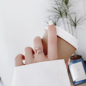Detail of rose gold flower ring with crystal stones on hand holding a coffee cup